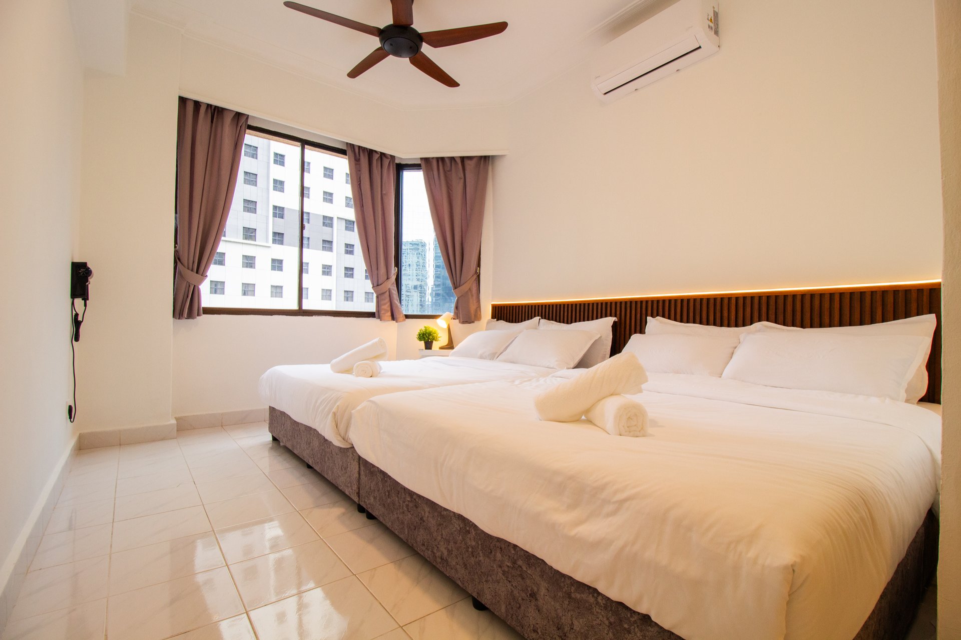 Downtown Condominium KL guest bedroom with three beds and city-facing windows